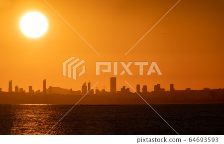 Huge sun and sunset over Benidorm city skyline and sea Huge sun and sunset over Benidorm city skyline and sea 64693593