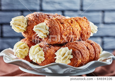 Dessert tubes with cream in front of a brick wall 64694106