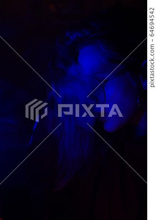 Close up portrait of vaping girl in neon blue light Close up portrait of vaping girl in neon blue light 64694542