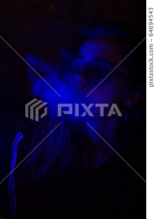 Close up portrait of vaping girl in neon blue light Close up portrait of vaping girl in neon blue light 64694543