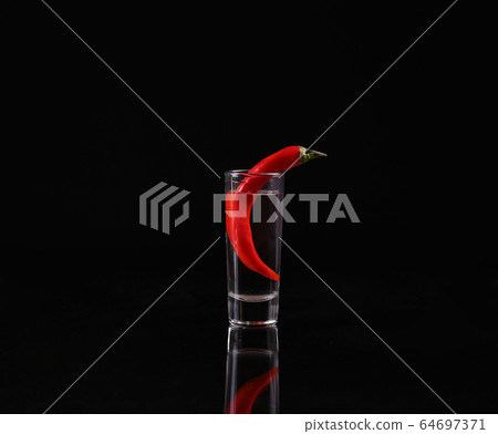 Shot of vodka with chili peppers on a black Shot of vodka with chili peppers on a black 64697371