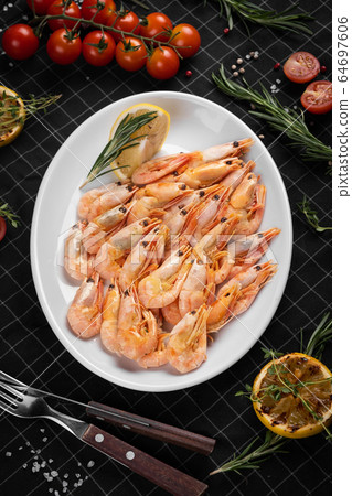 Boiled king prawns on a white plate. Decorated with a slice of lemon. 64697606