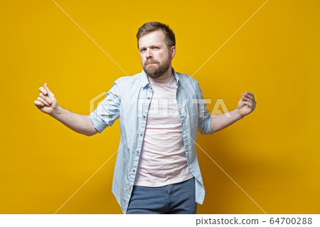 Stylish, sexy bearded man snaps fingers and dances with a passionate look, on a yellow background. Stylish, sexy bearded man snaps fingers and dances with a passionate look, on a yellow background. 64700288