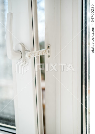 Open white PVC window with a fixing device for ventilation, in natural light. Horizontal photo. Open white PVC window with a fixing device for ventilation, in natural light. Horizontal photo. 64700289