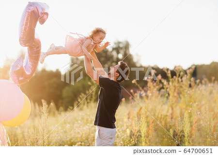 Dad and daughter are walking on the street at sunset. Dad throws up his daughter in his arms. happy family moments Dad and daughter are walking on the street at sunset. Dad throws up his daughter in his arms. happy family moments 64700651