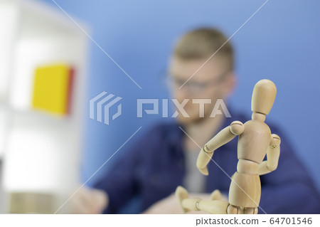Thoughtful focused young designer draws with pencil in studio with wooden dummy Thoughtful focused young designer draws with pencil in studio with wooden dummy 64701546