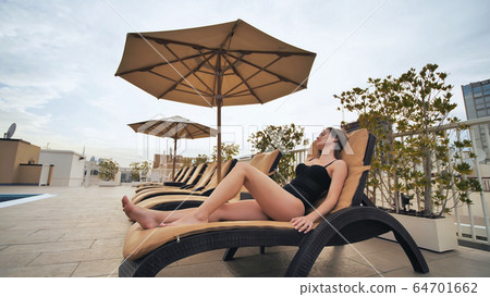 The girl lies on a sunbed on the roof of the hotel. The girl lies on a sunbed on the roof of the hotel. 64701662