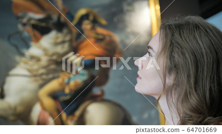 A girl examines a picture in a museum. A girl examines a picture in a museum. 64701669