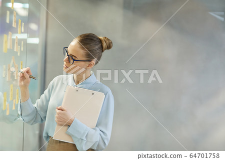Businesswoman making notes at office Businesswoman making notes at office 64701758