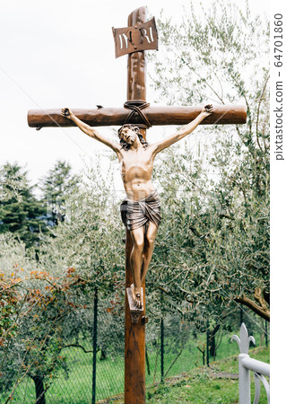 The crucifixion of Jesus Christ. A wooden statue in the park, among the olive trees. 64701860