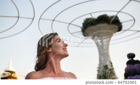Girl on the background futuristic metal flowers in Dubai Miracle Garden Park. Girl on the background futuristic metal flowers in Dubai Miracle Garden Park. 64702001