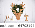 Christmas wreath made of fir branches and a Christmas deer head made of wood hanging 64702194