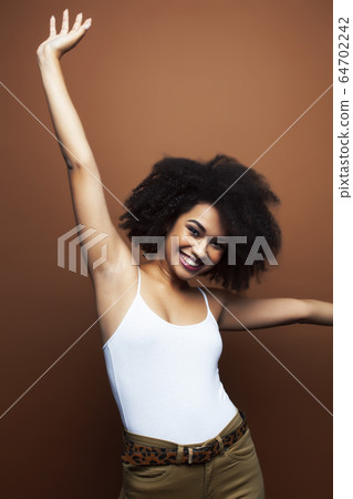pretty young african american woman with curly hair posing cheerful gesturing on brown background, lifestyle people concept pretty young african american woman with curly hair posing cheerful gesturing on brown background, lifestyle people concept 64702242