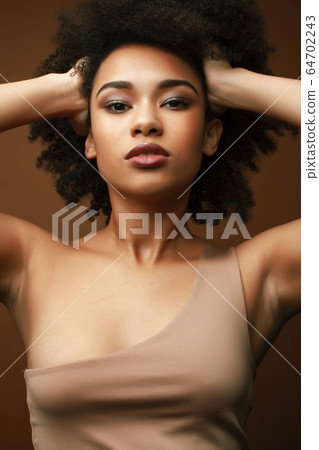 pretty young african american woman with curly hair posing cheerful gesturing on brown background, lifestyle people concept pretty young african american woman with curly hair posing cheerful gesturing on brown background, lifestyle people concept 64702243