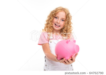 attractive curly european girl holding a piggy bank in her hands on a light blue background attractive curly european girl holding a piggy bank in her hands on a light blue background 64702790