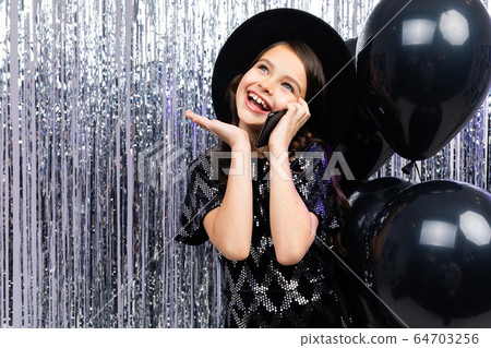 teenager girl talking on the phone at a party among black helium balloons and tinsel with copy space teenager girl talking on the phone at a party among black helium balloons and tinsel with copy space 64703256