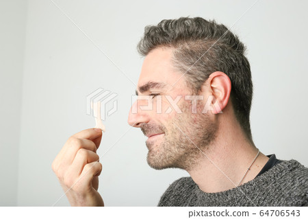 Man observing a new nasal strip, external nasal dilator strip Man observing a new nasal strip, external nasal dilator strip 64706543