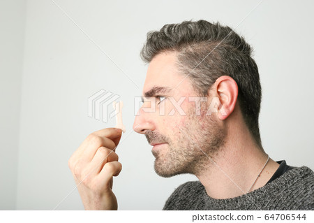 Man observing a new nasal strip Man observing a new nasal strip 64706544