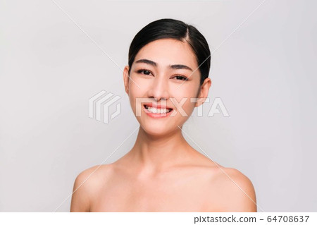 young beautiful asian woman with clean and bright skin, Cosmetic Beauty Concept,hands touch on the cheek, smiling and friendly face isolated on grey background 64708637
