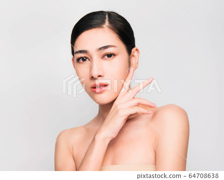 young beautiful asian woman with clean and bright skin, Cosmetic Beauty Concept,hands touch on the cheek, smiling and friendly face isolated on grey background 64708638