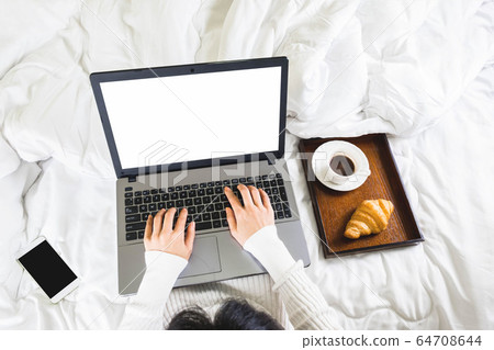 Selective focus,top view woman's hand typing on keyboard,croissant,coffee and mobile phone in white bedroom,work online lifestyle,relax at home 64708644