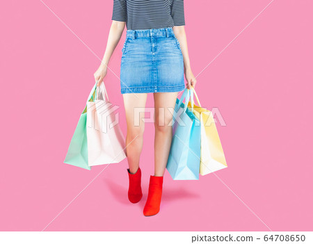 The woman low body part wore Denim skirt and red boots. Carrying a shopping bag in many pastel colors on pink background selective focus with copy space The woman low body part wore Denim skirt and red boots. Carrying a shopping bag in many pastel colors on pink background selective focus with copy space 64708650