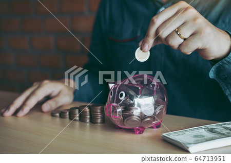 Men are holding coins dropping to the piggy bank 64713951