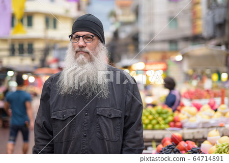 Mature bearded tourist man with eyeglasses thinking in Chinatown 64714891