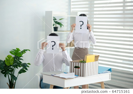 Male and female colleagues holding papers with question marks 64715161