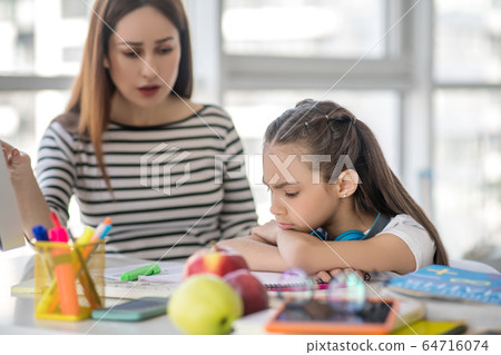 Mom doing lessons with her daughter at home. 64716074
