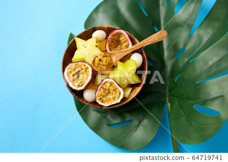 mix of exotic fruits in wooden plate with spoon mix of exotic fruits in wooden plate with spoon 64719741