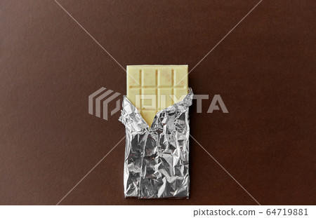 white chocolate bar in foil wrapper on brown white chocolate bar in foil wrapper on brown 64719881