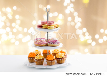 glazed donuts, cupcakes and macarons on stand 64719913