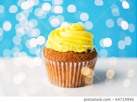 close up of cupcake or muffin with yellow frosting 64719998