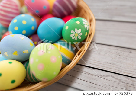 close up of colored easter eggs in basket 64720373