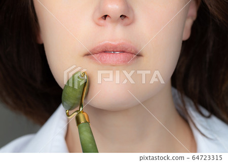 Woman with jade face roller 64723315