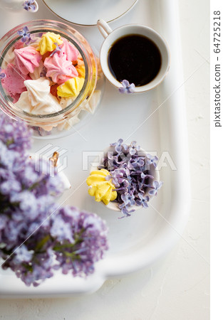 Breakfast with black tea or coffee and sweet meringue kisses on the white table. Breakfast with black tea or coffee and sweet meringue kisses on the white table. 64725218