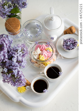 Breakfast with black tea or coffee and sweet meringue kisses on the white table. Breakfast with black tea or coffee and sweet meringue kisses on the white table. 64725221
