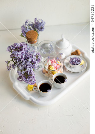 Breakfast with black tea or coffee and sweet meringue kisses on the white table. Breakfast with black tea or coffee and sweet meringue kisses on the white table. 64725222
