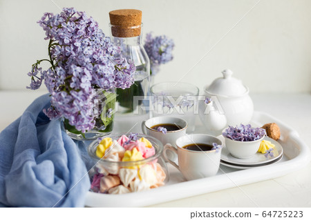 Breakfast with black tea or coffee and sweet meringue kisses on the white table. Breakfast with black tea or coffee and sweet meringue kisses on the white table. 64725223