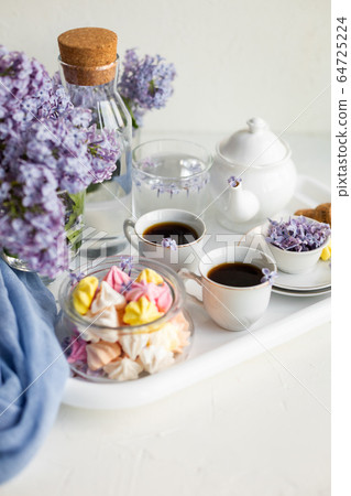 Breakfast with black tea or coffee and sweet meringue kisses on the white table. Breakfast with black tea or coffee and sweet meringue kisses on the white table. 64725224