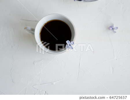 Black coffee or tea in the morning. Some fresh lilac flowers on the white table. Spring concept of breakfast. Black coffee or tea in the morning. Some fresh lilac flowers on the white table. Spring concept of breakfast. 64725637