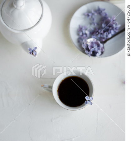 Black coffee or tea in the morning. Some fresh lilac flowers on the white table. Spring concept of breakfast. Black coffee or tea in the morning. Some fresh lilac flowers on the white table. Spring concept of breakfast. 64725638