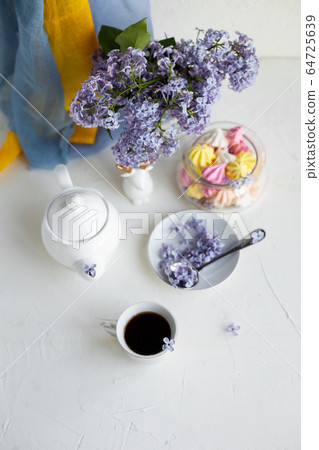 Black coffee or tea in the morning. Some fresh lilac flowers on the white table. Spring concept of breakfast. Black coffee or tea in the morning. Some fresh lilac flowers on the white table. Spring concept of breakfast. 64725639