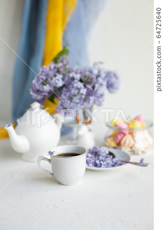 Black coffee or tea in the morning. Some fresh lilac flowers on the white table. Spring concept of breakfast. Black coffee or tea in the morning. Some fresh lilac flowers on the white table. Spring concept of breakfast. 64725640