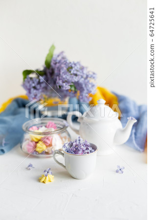 Black coffee or tea in the morning. Some fresh lilac flowers on the white table. Spring concept of breakfast. Black coffee or tea in the morning. Some fresh lilac flowers on the white table. Spring concept of breakfast. 64725641