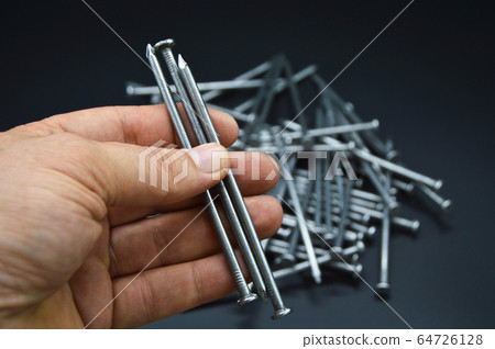 Pile of construction iron nails on hand 64726128