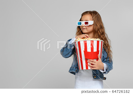 child girl wearing red-blue 3d glasses having fun and holding popcorn bucket child girl wearing red-blue 3d glasses having fun and holding popcorn bucket 64726182