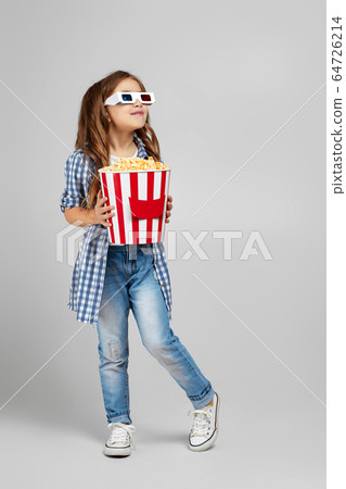 child girl wearing red-blue 3d glasses and eating popcorn child girl wearing red-blue 3d glasses and eating popcorn 64726214
