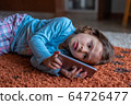 Cute little girl lying down looking at mobile 64726477